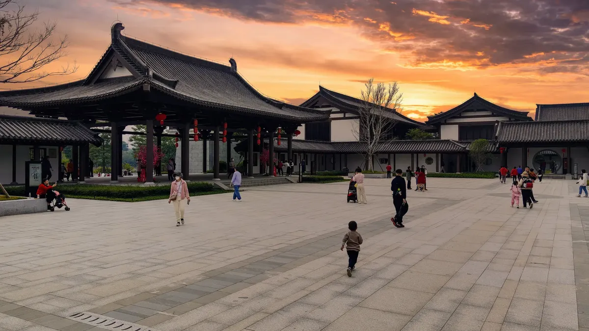 A stunning view of traditional Chinese architecture at sunset in Guangzhou, China, with people enjoying the evening.