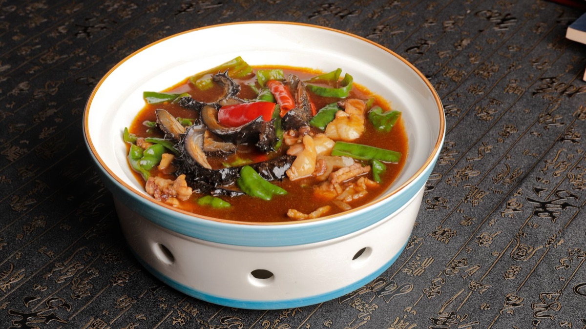 Chinese family cooking stew in traditional kitchen