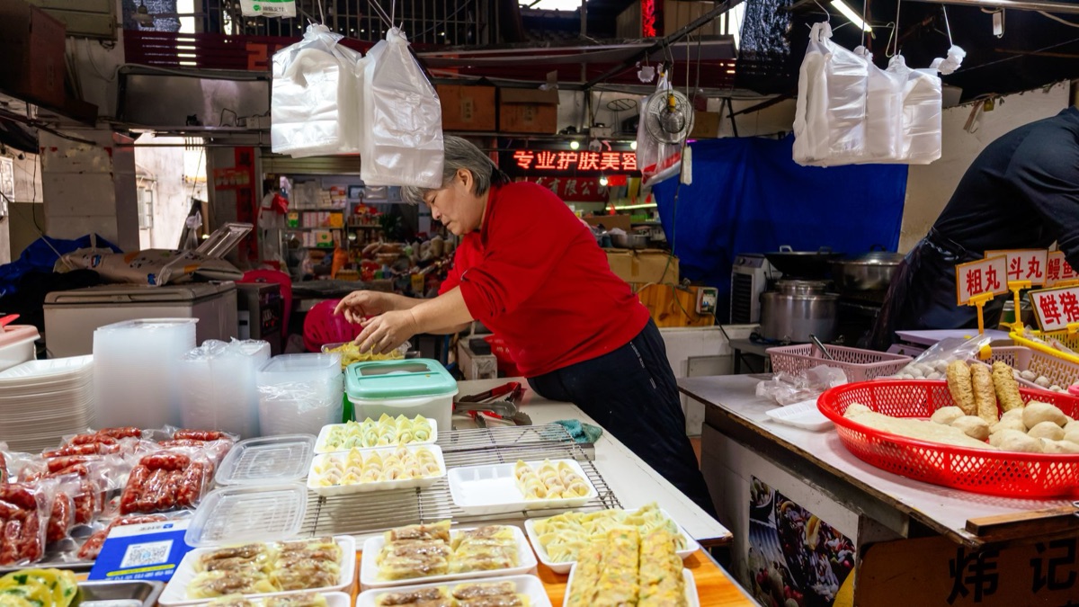 Un venditore di cibo stradale cinese con skewers di rolli di primavera