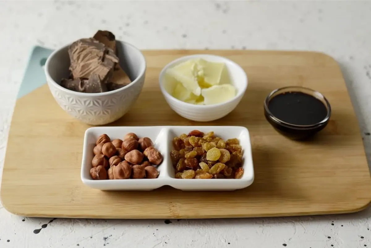Close-up of baking ingredients like chocolate, hazelnuts, raisins and butter on a wooden board, perfect for dessert recipes.