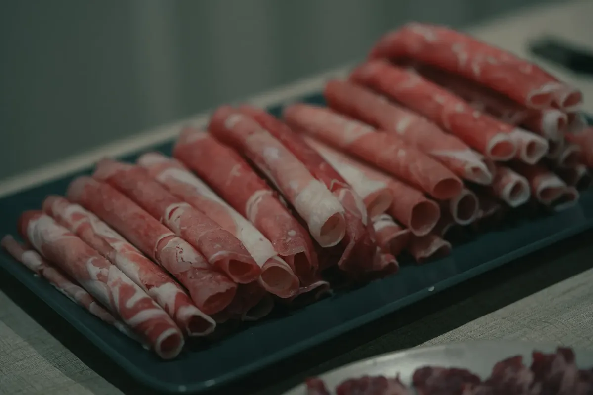 Close-up of rolled lamb slices on a plate, perfect for hot pot or grilling.