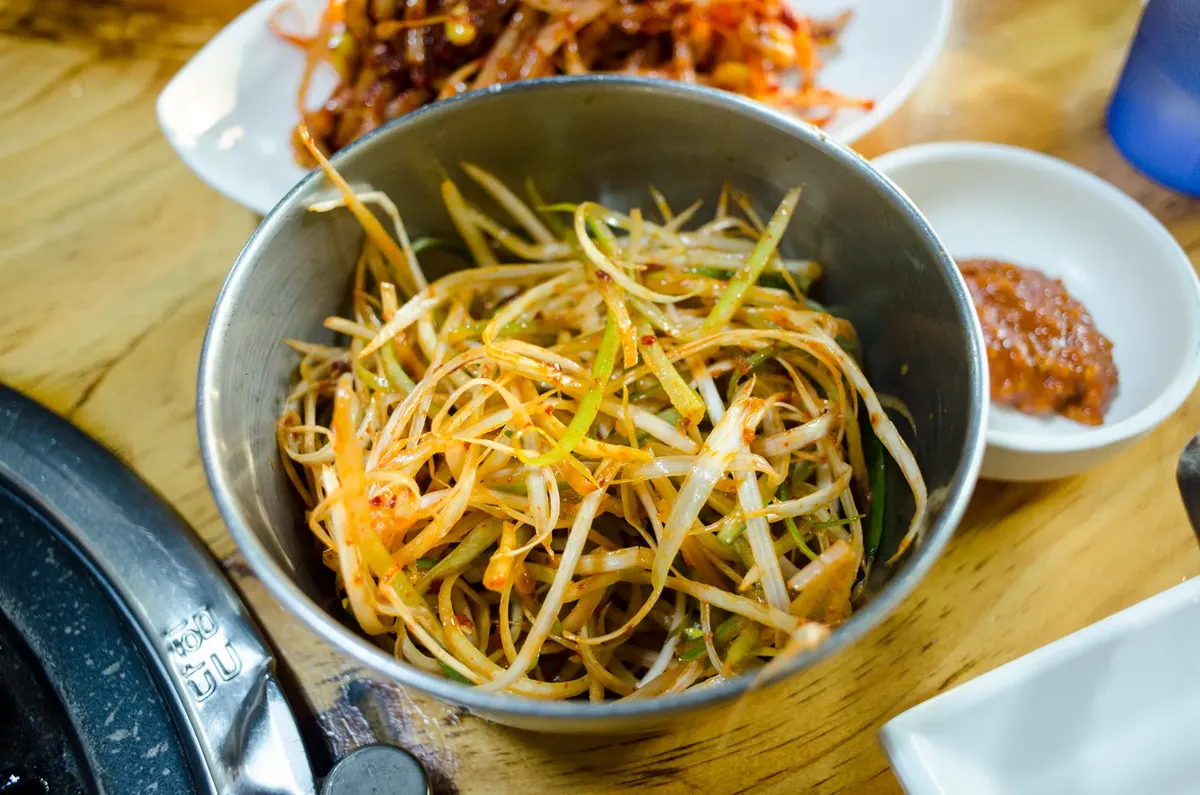 Close-up of spicy Korean green onion salad served as a side dish in a metal bowl.