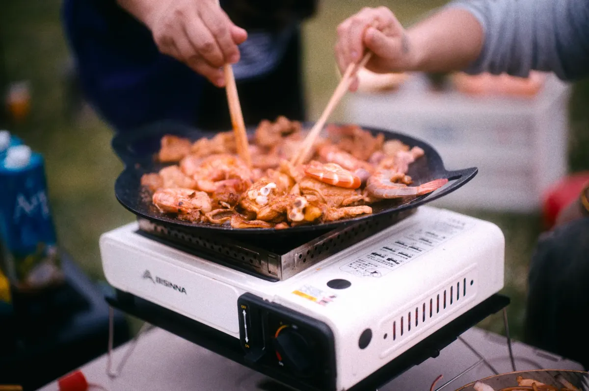 People grilling seafood outdoors in Chengdu, showcasing a lively and vibrant cooking scene.